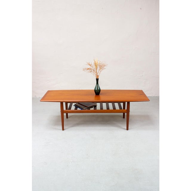 A beautiful Danish teak coffee table designed by Grete Jalk. The elongated tabletop, with its rounded corners and softly...
