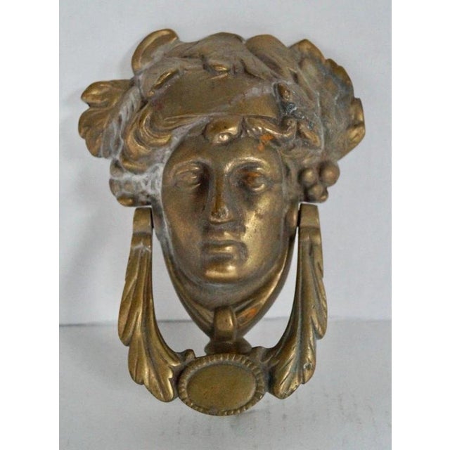 A distinctive Victorian cast brass door knocker dating to circa 1900, modelled as the head of Dionysus crowned with an ivy...