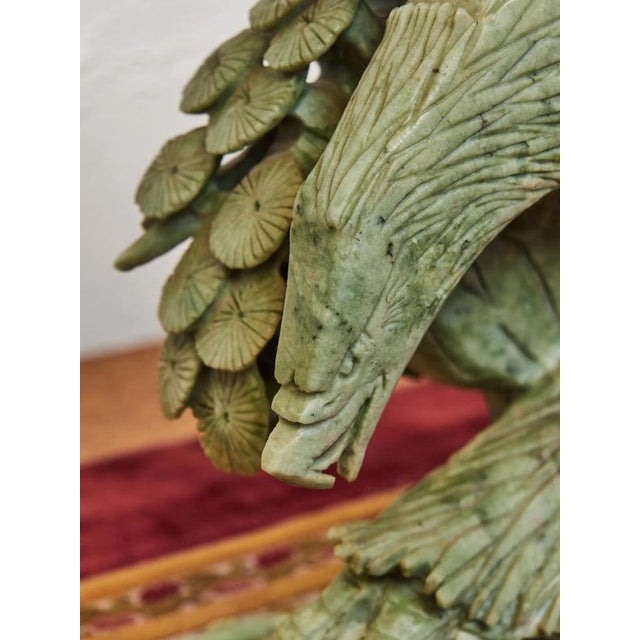 A distinctive stylized statue of an eagle with outstretched wings, masterfully carved from a solid block of green...