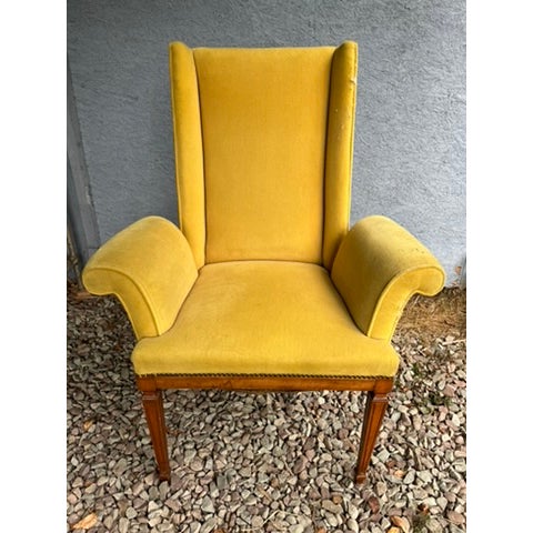 A single vintage wood frame armchair featuring curved flared arms, square seat back with wings, and nailhead trim.
