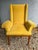 A single vintage wood frame armchair featuring curved flared arms, square seat back with wings, and nailhead trim.