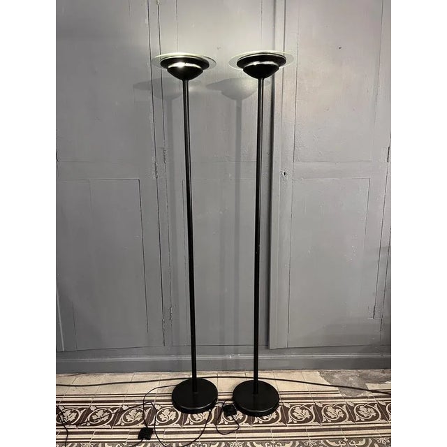 Large pair of floor lamps in black lacquered metal. The diffuser is composed of a large glass disc and a perforated metal...