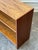 This 1970s low bookcase is made of a warm teak veneer that highlights a natural wood grain pattern across the top and side...