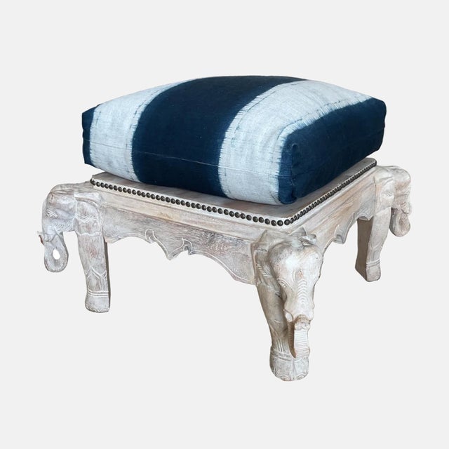 blue and white cushion ottomans with elephant carvings.
