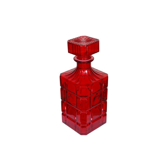 A crystal ‘Radius’ decanter with stopper by Godinger. Square and ruby red, with square facets decorating the sides and a...