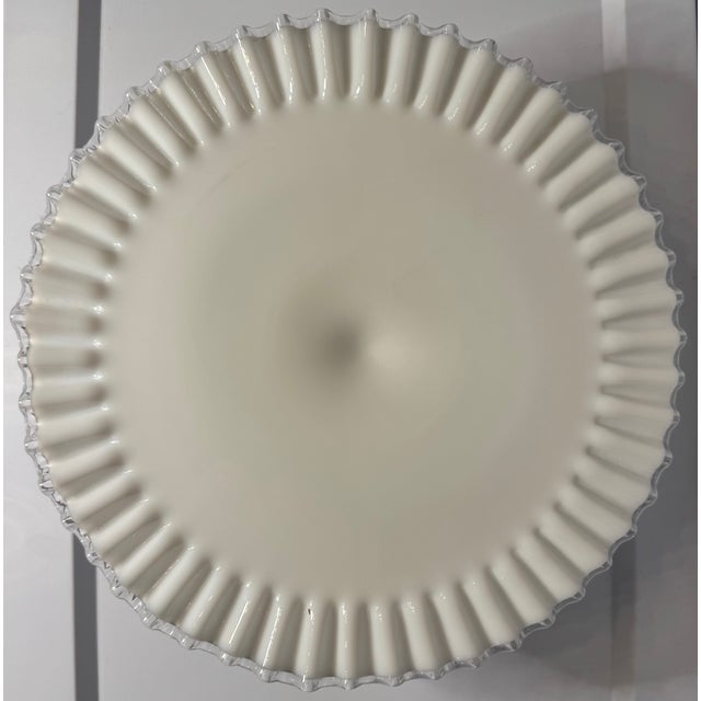 A timeless Fenton Silver Crest cake stand featuring luminous milk glass and a delicately ruffled clear edge—an elegant...