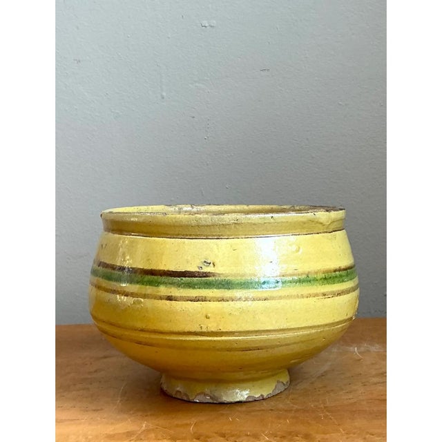 This earthenware bowl commands attention through its confident, rounded silhouette and the horizontal banding that wraps...