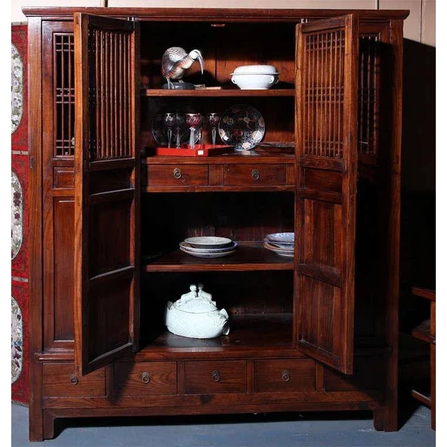 This large and unusual Anglo-Chinese, turn-of-the century elmwood armoire displays accordion openwork doors with two...