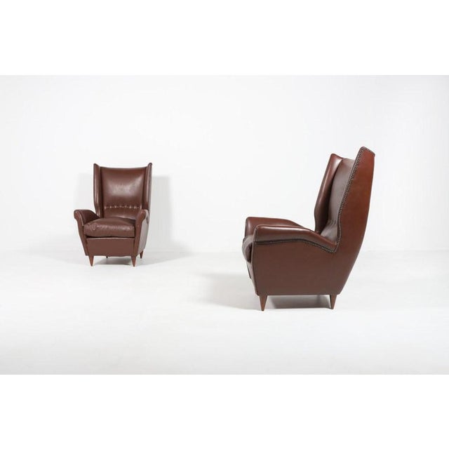 Pair of 2 spectacular Wingback Lounge armchairs in brown leather on stained wood legs, loose sitting cushions. 1950s. The...