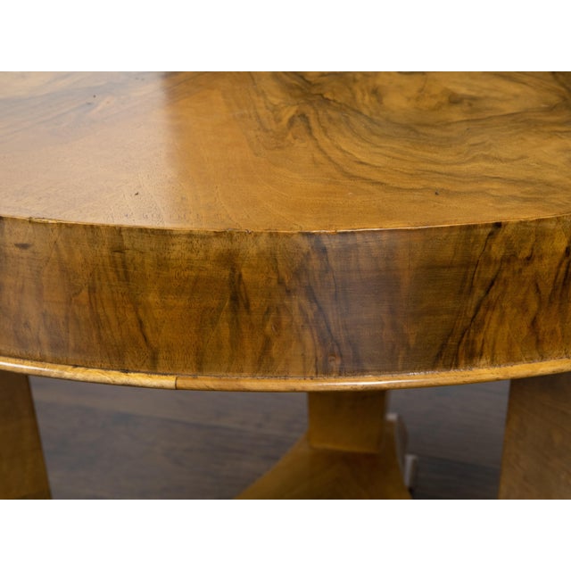 An Austrian Biedermeier period walnut center table from the mid 19th century, with butterfly veneered top, tripod base and...