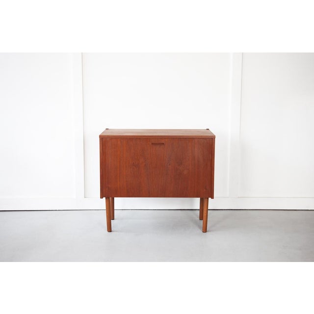 A very sweet and petit teak cabinet from Denmark with a hinged door which opens to reveal an open storage compartment....