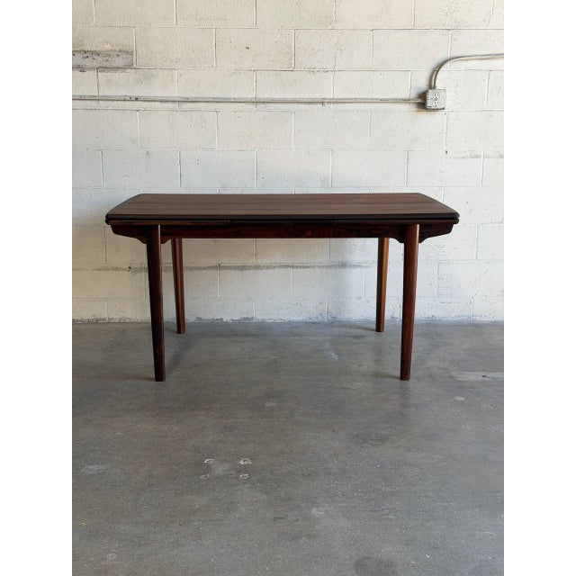 This minimalist dining table features a rectangular top that pulls apart to accommodate two integrated draw-out extension...