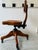 A beautifully restored vintage wooden stenographer chair featuring sculpted solid oak construction, adjustable seating,...
