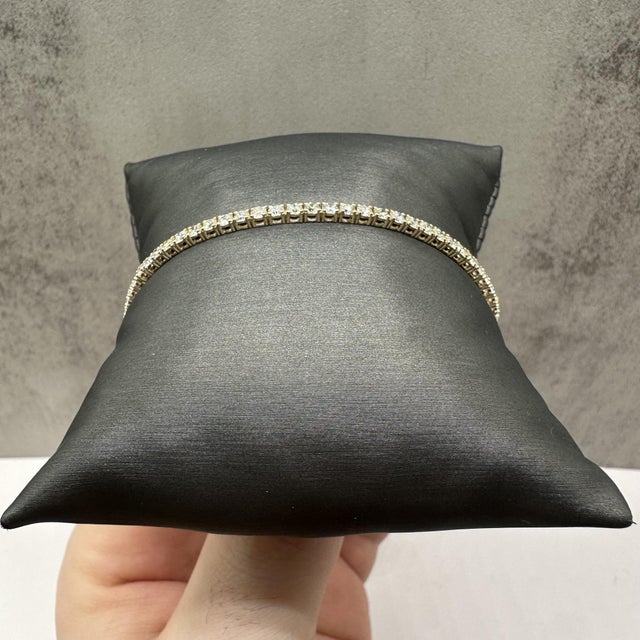 This elegant natural diamond tennis bracelet in 14kt yellow gold features 3.1 carats total weight of GH SI2–I1 round...