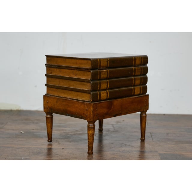 A small English Victorian period faux book trunk on base from the 19th century with cylindrical tapering legs. This...
