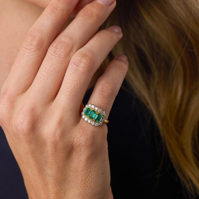 This striking Retro English ring showcases three beautifully matched rectangular cushion cut emeralds totaling...