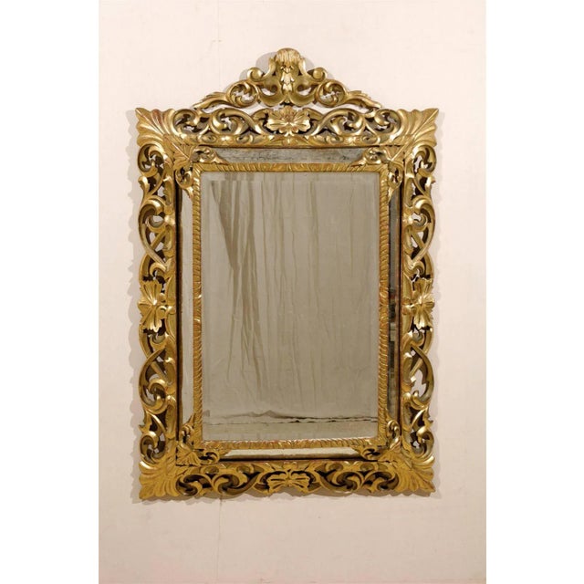 An exquisite Italian carved and gilded mirror from the 19th century. This ornate mirror features an intricately carved...
