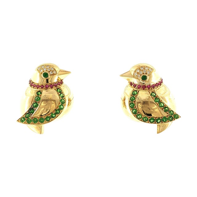 A pair of fine-quality late 20th-century 18k gold bird-shaped earrings. Adorned with round green garnets and red rubies....