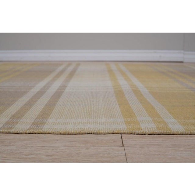 This hand knotted pile rug features a primary color palette of yellow, gold, and orange tones. Crafted from natural wool,...