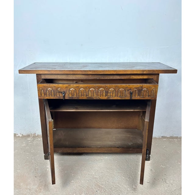 Mid 20th century Spanish rustic commode crafted in solid wood with a warm aged patina. The piece features a single upper...