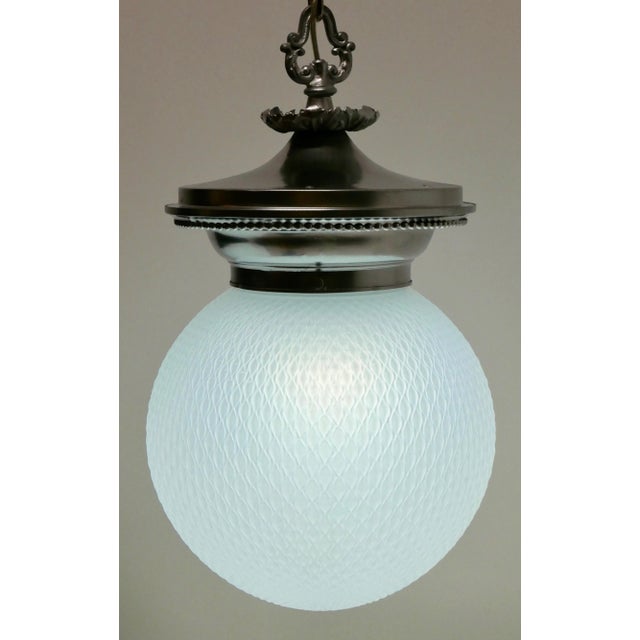 Attractive antique hanging opaline glass globe and cast metal pendant. The opaline globe has a subtle fishnet pattern and...