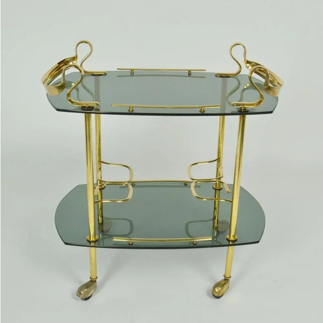 This is an unusual elegant bar cart, cocktail or serving trolley in brass and smoked glass Italy circa 1960's. The...