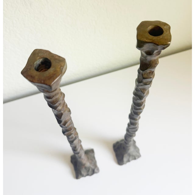 A pair of Brutalist candle holders, circa 1960s, in the style of Alberto Giacometti. The heavy cast bronze metal, weighing...