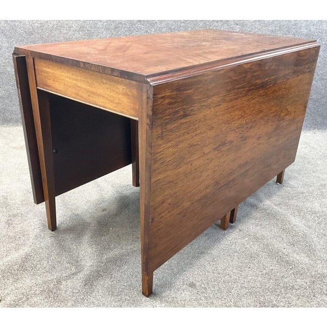 A beautifully proportioned antique mahogany drop-leaf dining table featuring exceptionally rich grain, slender tapered...