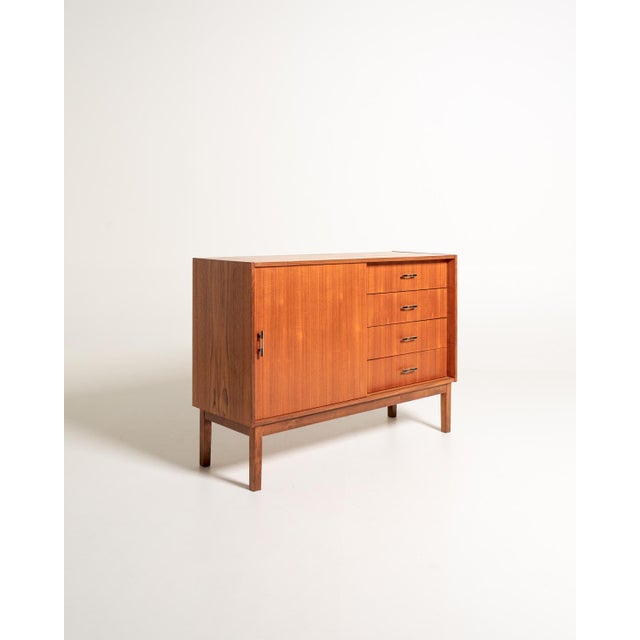 Teak sideboard with sliding door, internal shelf, and four side drawers. Metal and black Bakelite handles. Scandinavian...