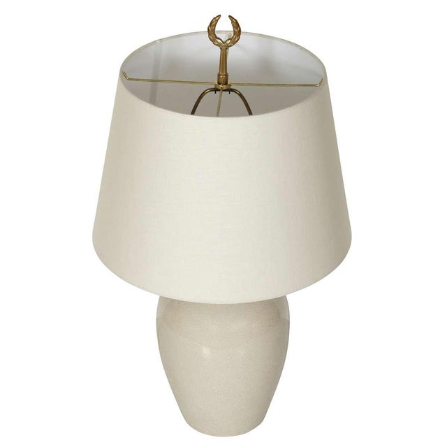 A pair of contemporary white ceramic lamps featuring a soft crackle-glaze finish and clean, rounded silhouettes. Each lamp...