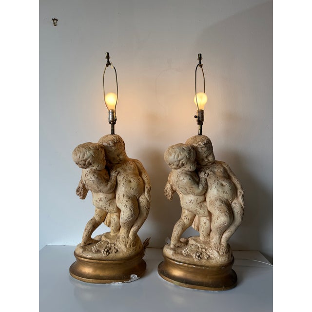 Elegant pair of vintage French table lamps featuring sculptural putti (cherubs) in an intimate embracing pose, inspired by...