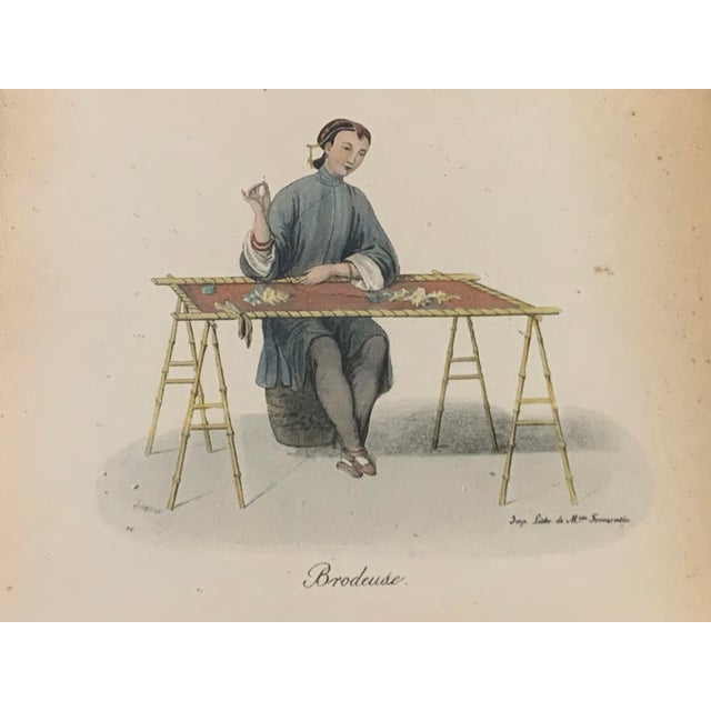 A refined mid-19th-century French hand-colored lithograph titled “Brodeuse” (Embroiderer), depicting a seated artisan...