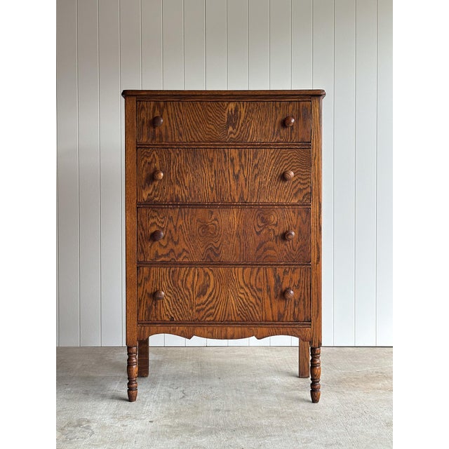 This antique five-drawer dresser features a narrow upright silhouette with richly figured tiger oak grain, turned front...