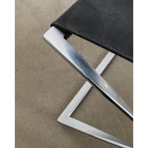 A rare and early danish mid century folded "pk91" stool in brushed chromed steel with a black leather seat designed by...
