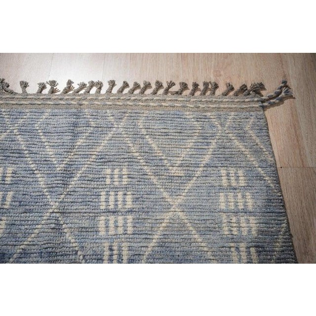 This blue wool rug features a hand knotted pile construction and is styled as a Berber carpet. Originating from Pakistan,...