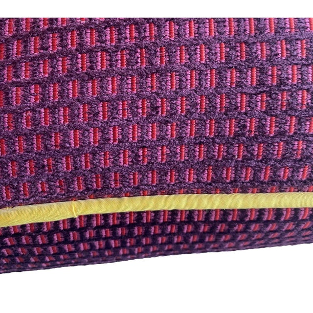 This pillow features a textured woven pattern in deep purples, creating a dynamic, grid-like effect. The yellow welt adds...