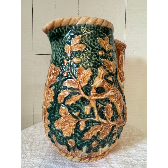 Fun vintage majolica style pottery pitcher with a squirrel enjoying acorns on an oak tree The handle is styled to resemble...