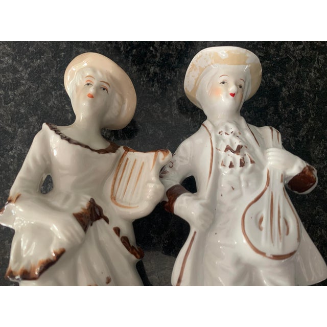 Set of 2 ceramic figurines Embossed signature "A" A pair of ceramic figurines of a man and a woman. The man has an...