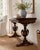 A beautifully carved antique walnut flip-top game table featuring dramatic pedestal urn supports, carved detailing, and a...