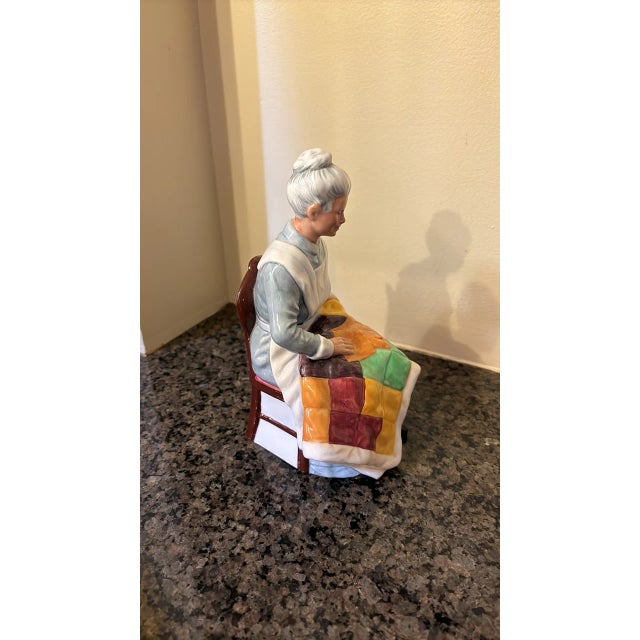 This Royal Doutlon figurine depicts a woman with a colorful patchwork quilt. It is made of bone china/porcelaine and...