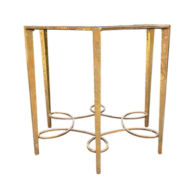 A striking entryway or center table in distressed gilt metal with a black granite top and looping base. Maker is unknown