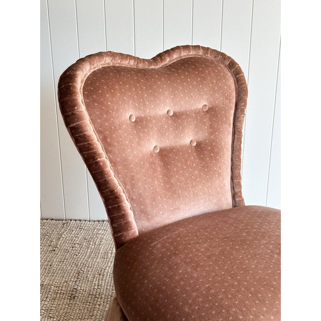This vintage slipper chair features a softly scalloped back with subtle button tufting and a low armless profile that...