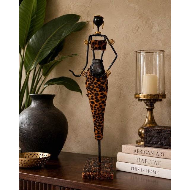 This vintage African-inspired handcrafted metal sculpture depicts a graceful female figure carrying a traditional vessel,...