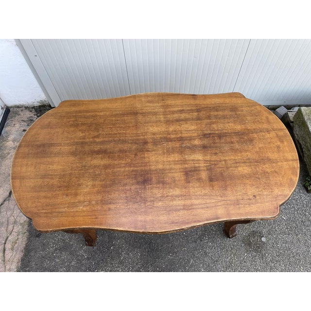 Dining table in walnut wood from the early 1900s, shaped oval shape. Saber legs, inlaid leaf-shaped decoration.