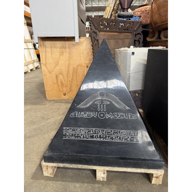 A bold solid black granite pyramid sculpture, polished to a high-gloss finish and engraved with Egyptian Revival motifs,...