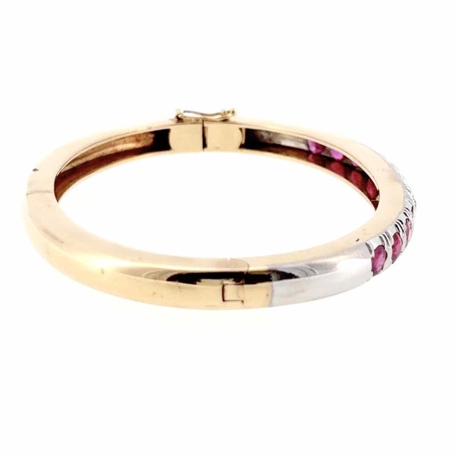 Vintage hinged bangle bracelet carfted in 14K yellow and white gold, featuring a sequence of round-cut red rubies and...