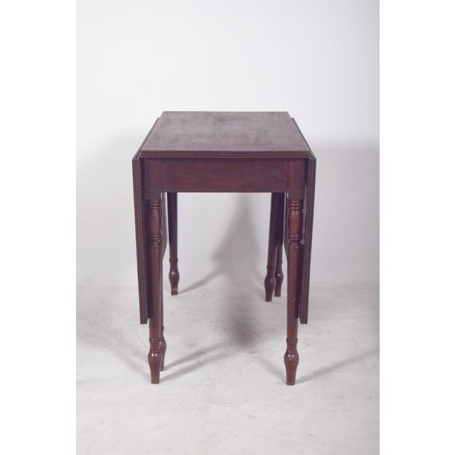 Square-top table. In dark wood, it has a polished finish, giving the piece a sober and timeless look. The top is made up...