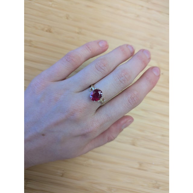 Inspired by nature, this stunning 3.9 carat Madagascar ruby ring features a rich, deep red center stone embraced by earth-...