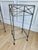 An elegant pair of vintage silvered iron pedestal tables featuring hand-forged construction, inset glass shelves, and...