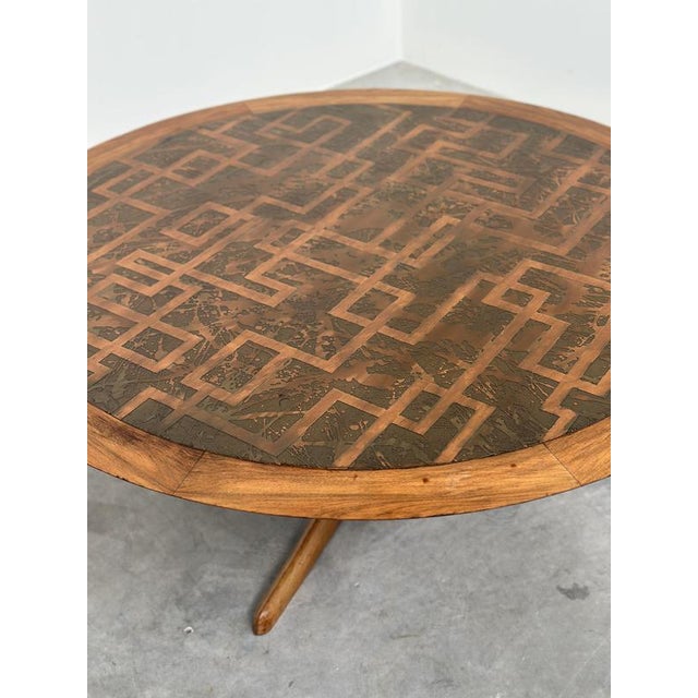 A striking vintage round coffee table combining warm-toned wood with an exceptionally decorative etched brass top. The...